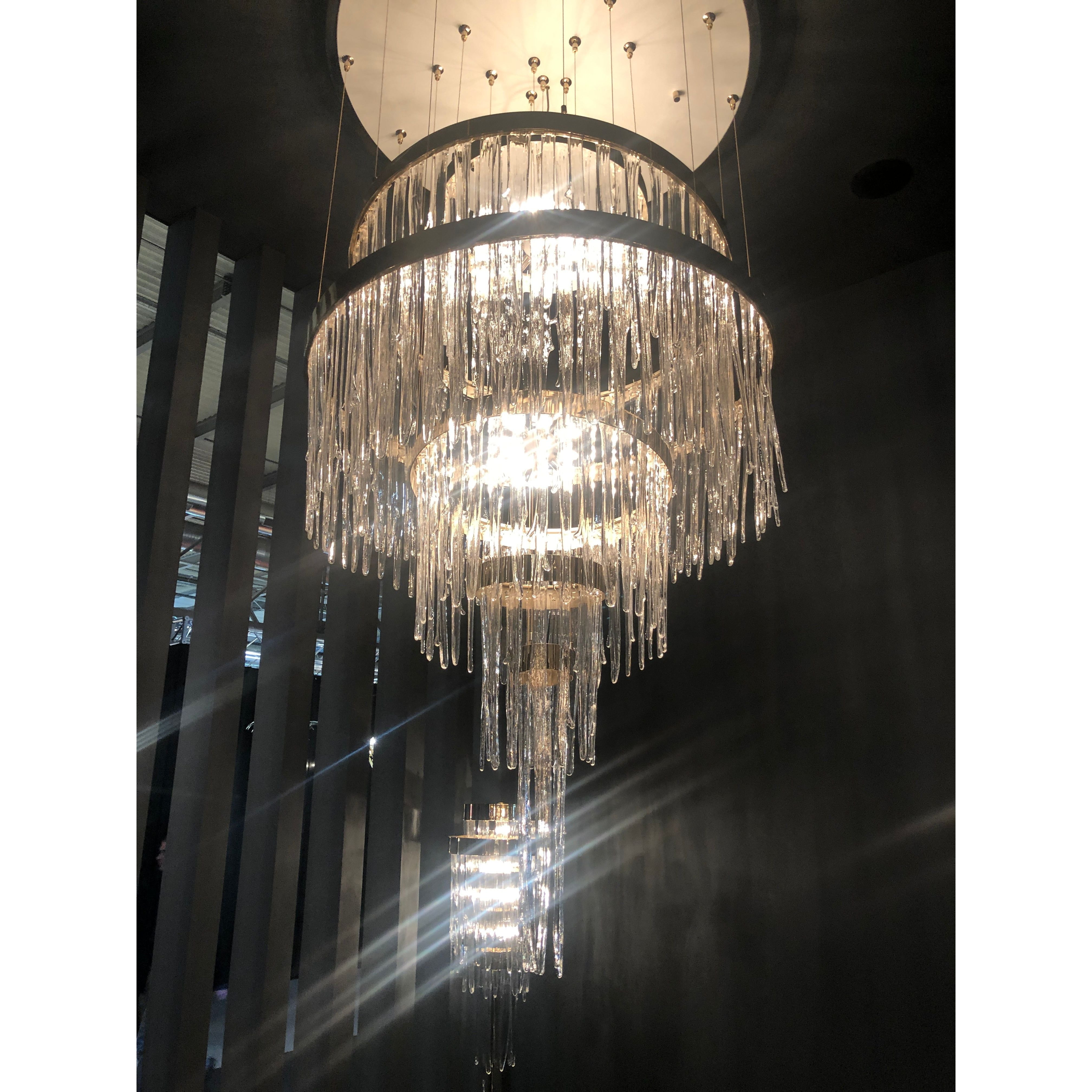 Modern brass chandelier with cascading crystals in a double height foyer, statement lighting for luxury interiors